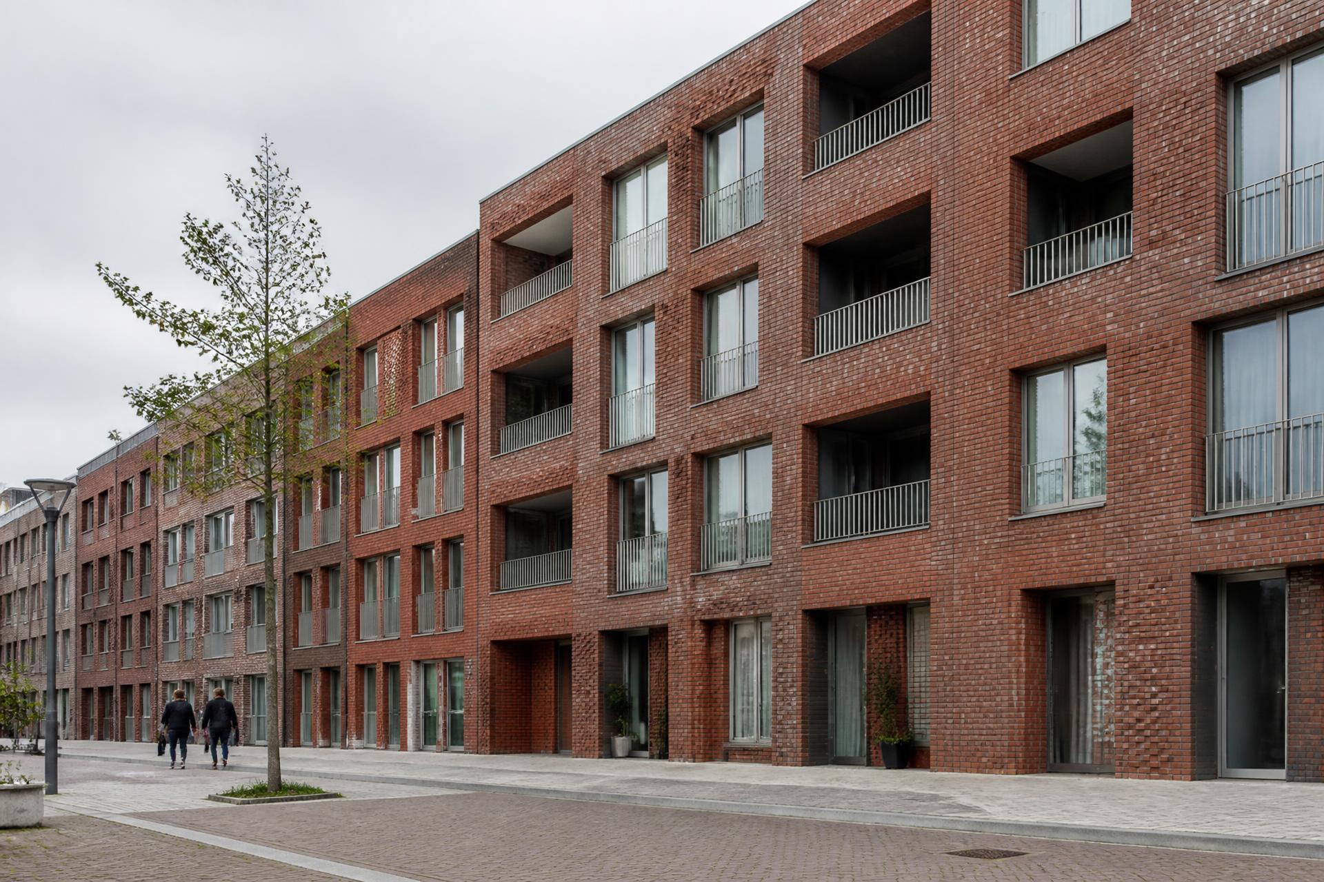 Nieuwe stedelijke woningbouw met bakstenen gevel en balkons aan een straat